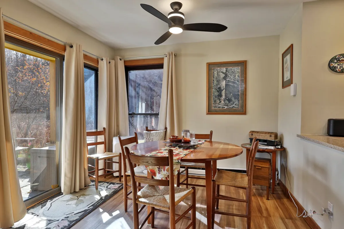 An inviting dining area featuring a sturdy dining table, large windows allowing natural light to pour in, and tasteful artwork on the walls. The setup is ideal for shared meals, conversations, and special moments.