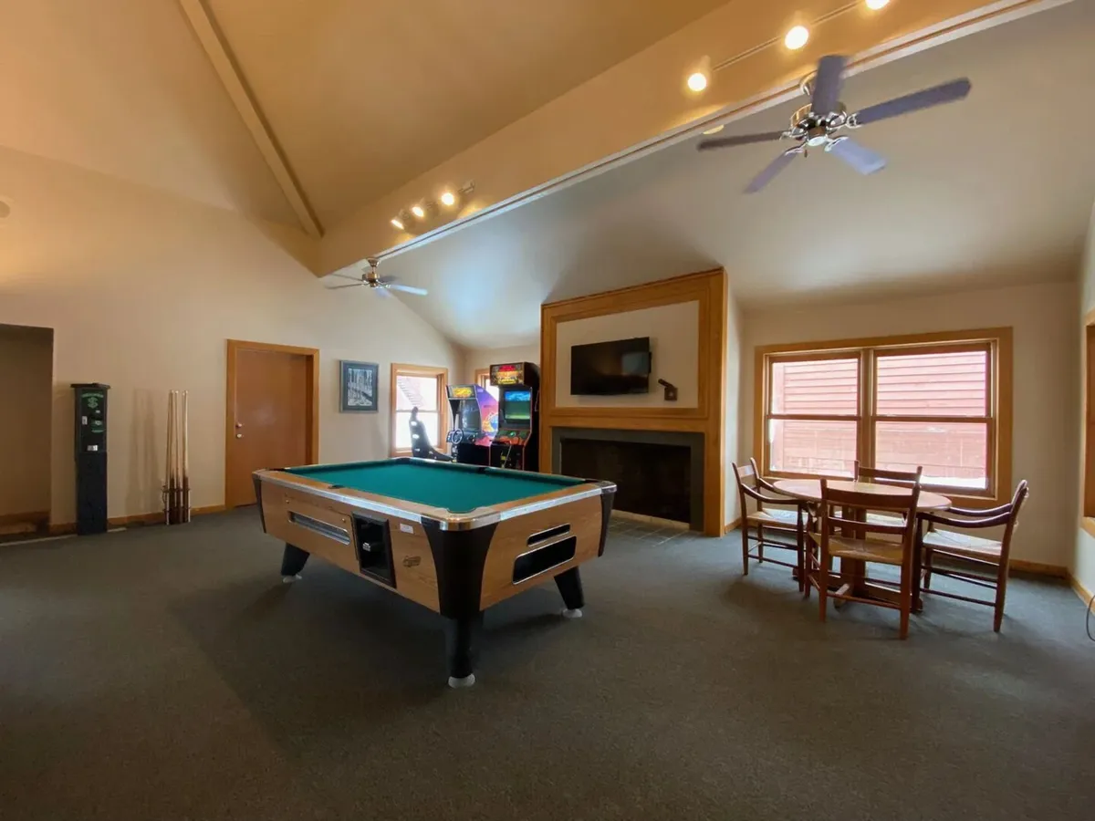 A lively game room with a pool table, arcade machine, cozy seating, and a fireplace. The space is designed for fun, socializing, and casual dining, making it a hub for guests of all ages.