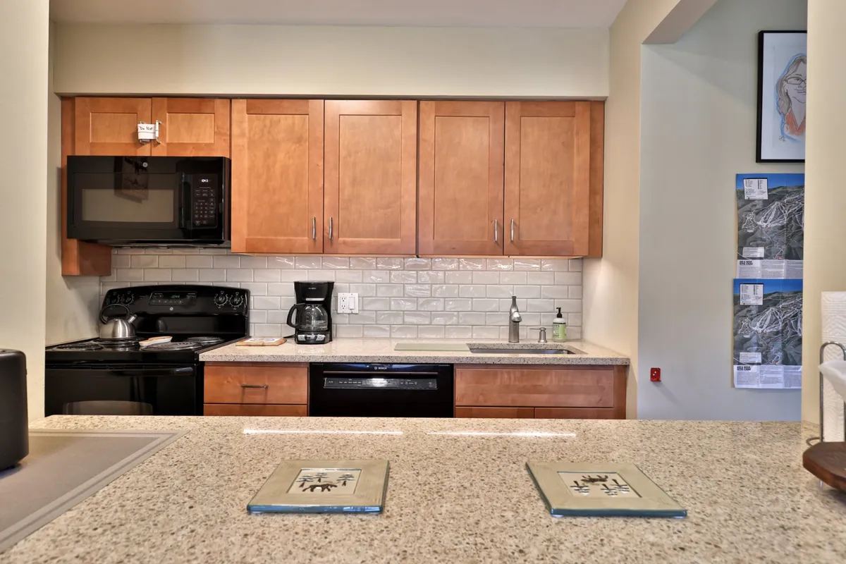 A cozy kitchen with a granite countertop, ample wooden cabinetry, and visible appliances. The space feels intimate and ready for both meal prep and socializing, with a sense of warmth and togetherness.